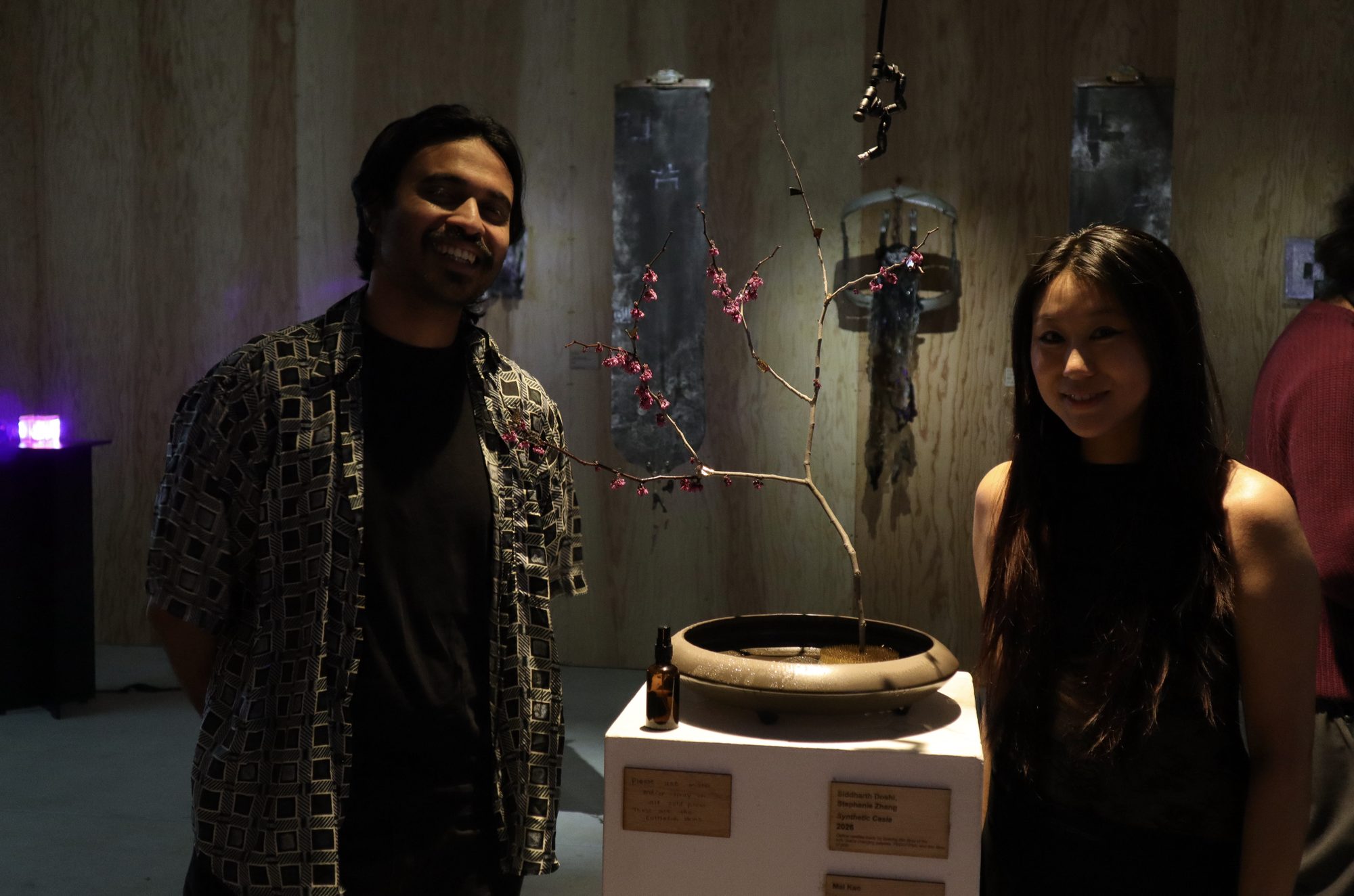 Two people smiling on either side of Synthetic Cesia on its plinth.